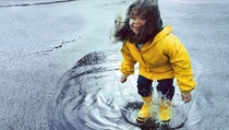 Girl (3-5) jumping in puddle wearing rain gear Girl (3-5) jumping in puddle wearing rain gear