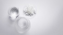 Crystal clear liquid in beaker, Flake salt in Chemical Watch Glass. Chemicals ingredients on laboratory table. Top View Crystal clear liquid in beaker, Flake salt in Chemical Watch Glass. Chemicals ingredients on laboratory table. Top View